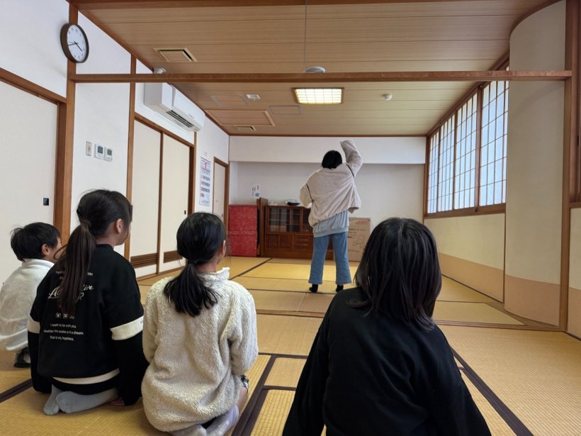 ジェスチャーをしているのを4人が見ている